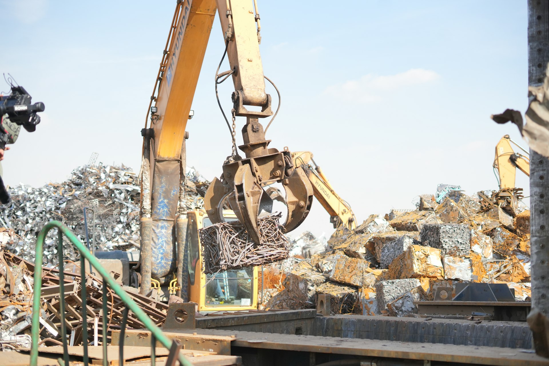 An excavator working on a pile of scrap metal